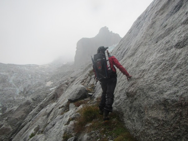 Alan Silva searching for a route up the rock buttress in the rain on day one of the climb