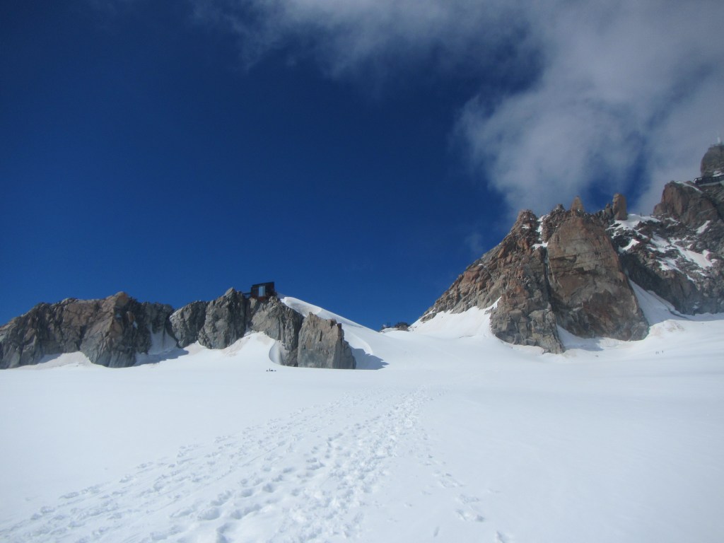Walking up the Valley Blance - a microwave oven of reflected sun off the snow and heat... The Refuge Cosmiques is on the left rock pinnacle while Aguille du Midi cable station is on top right side - 3800m