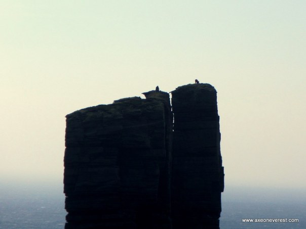 Two German climbers on their knees on the summit of the Old Man of Hoy in strong winds